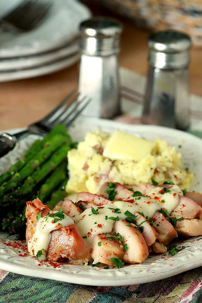 Buttermilk Roasted Chicken with Garlic and Brown Sugar on a White Plate with Mashed Potatoes and Asparagus