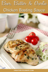 Beer, Butter, and Garlic Chicken Basting Sauce on Chicken Thighs Garnished with Herbs and Served on a White Plate with Tomatoes