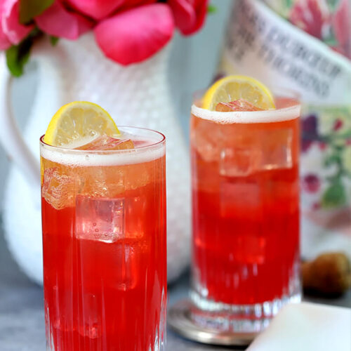 Sparkling Raspberry, Vodka, and Honey Cocktail Served in Two Highball Glasses and Garnished with Lemon