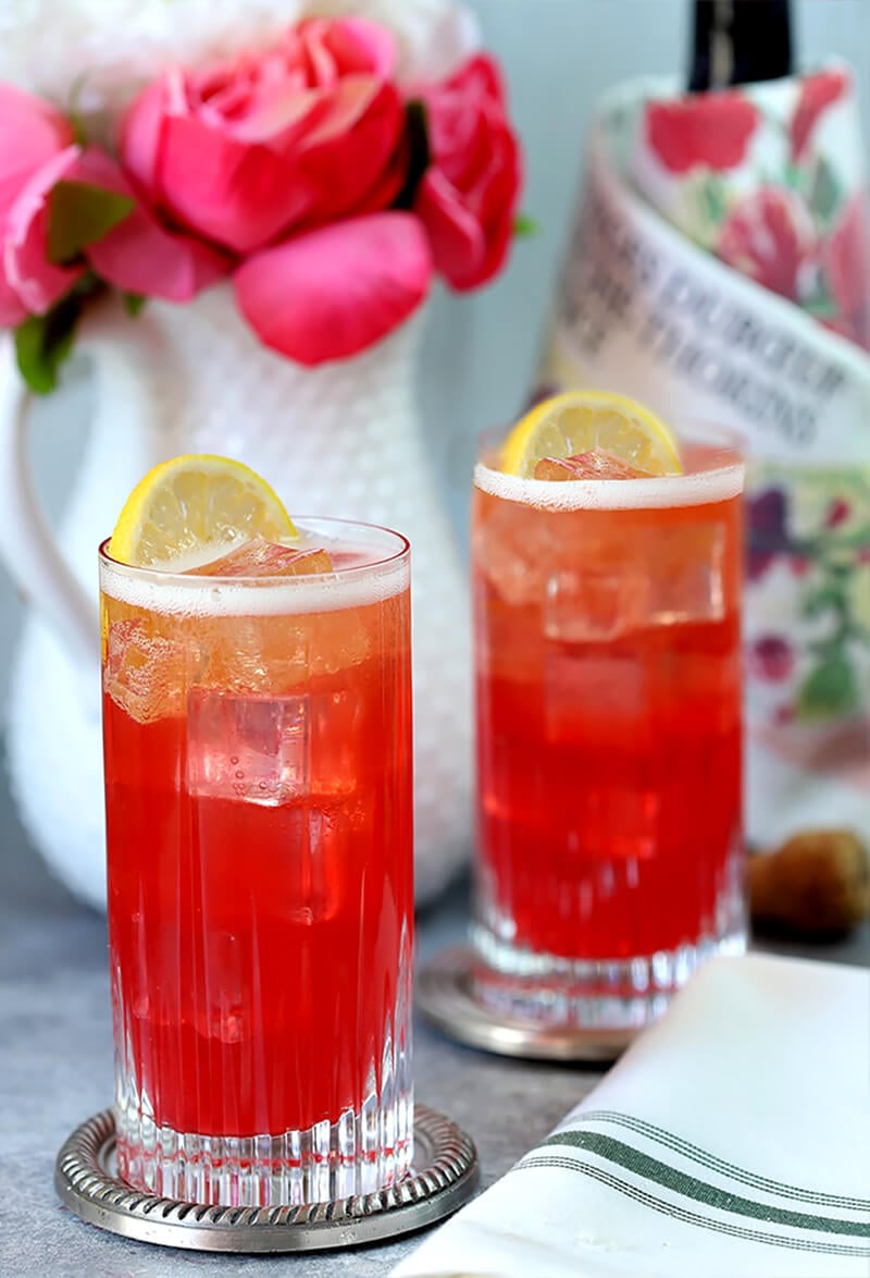 Sparkling Raspberry, Vodka, and Honey Cocktail Served in Two Highball Glasses and Garnished with Lemon