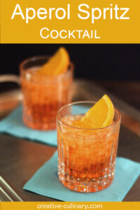 Pair of Aperol Spritz Cocktails served on turquoise napkins.