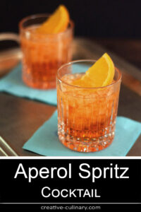 Pair of Aperol Spritz Cocktails served on turquoise napkins.