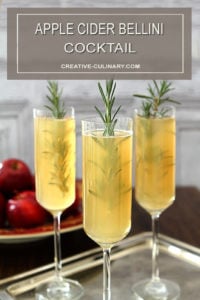 Apple Cider Bellini Cocktail in Champagne Glass Garnished with Sprig of Rosemary