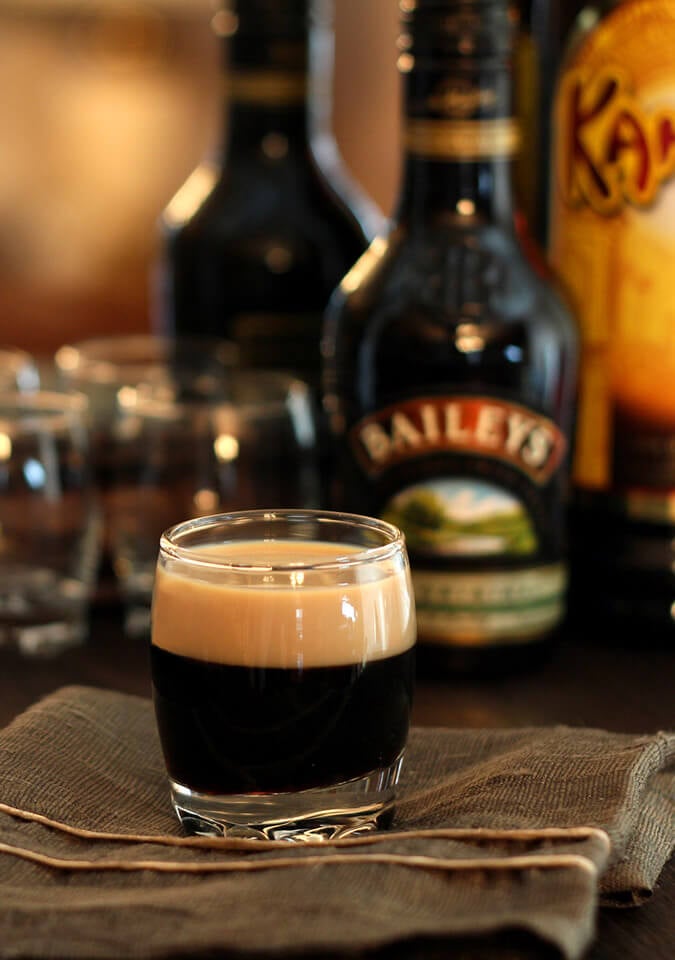 Small glass with a Baby Guinness Cocktail layering Kahlua with Baileys Irish Cream liqueurs.