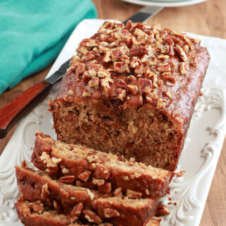 Bananas Foster Banana Bread on a serving plate with slices cut.