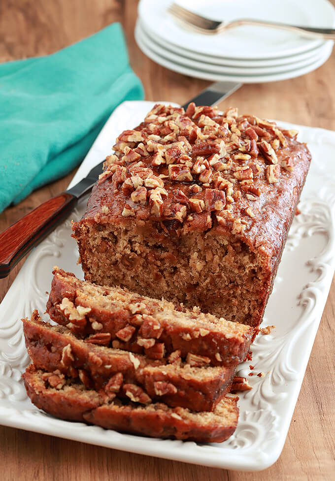 Bananas Foster Banana Bread on a serving plate with slices cut.