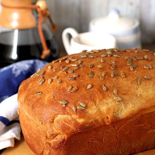 Billowy Off-White Bread with Milk and Honey Topped with Sunflower Seeds and Served on a Cutting Board