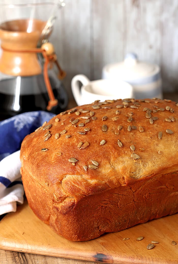 Billowy Off-White Bread with Milk and Honey Topped with Sunflower Seeds and Served on a Cutting Board