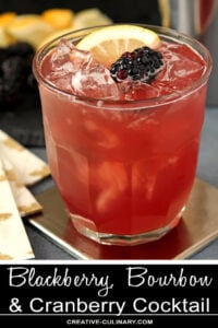 Blackberry, Bourbon, and Cranberry Cocktail Garnished with Blackberry and Lemon Wedge