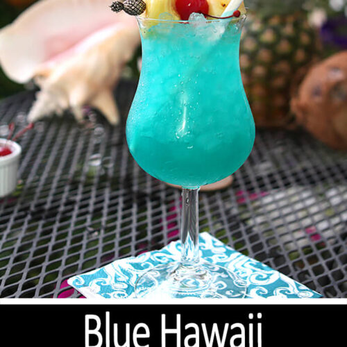 Blue Hawaii Cocktail served in a cocktail glass with both pineapple chunks and cherries for garnish.