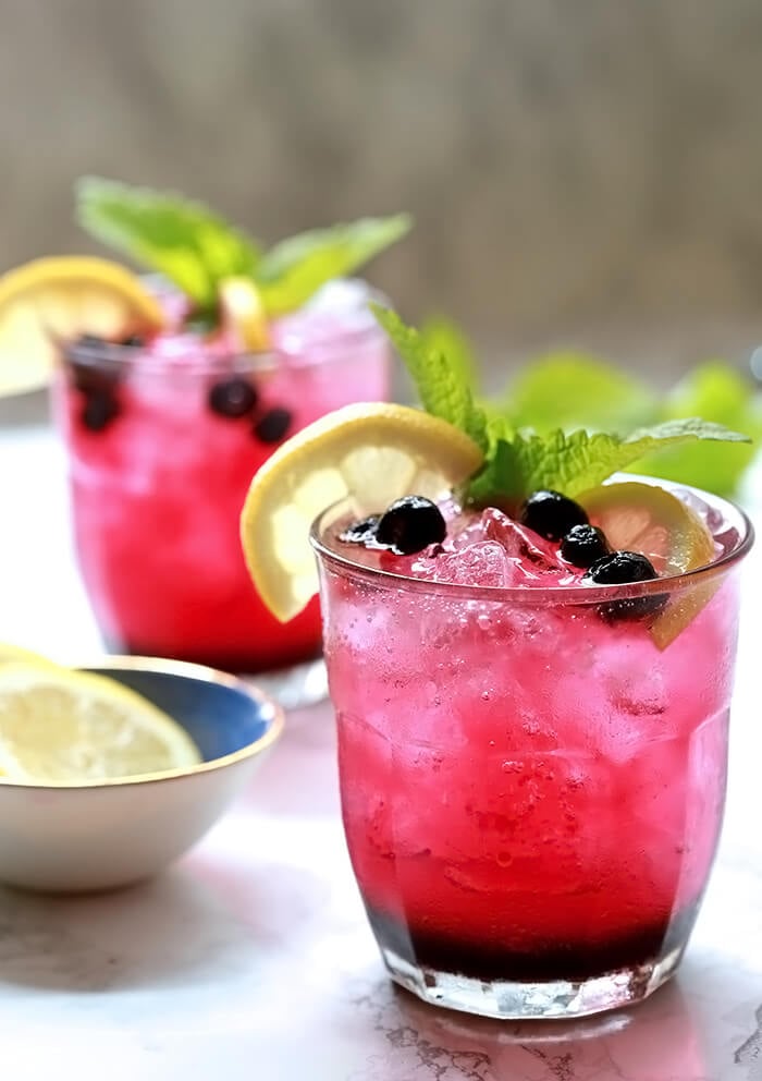 Sparkling Lemonade and Blueberry Cocktail on a White Marble Slab with Garnishes