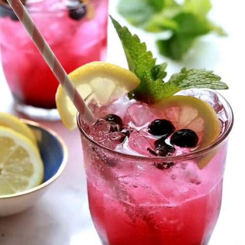 Two Sparkling Lemonade and Blueberry Cocktails with Lemon, Mint, and Blueberry Garnish