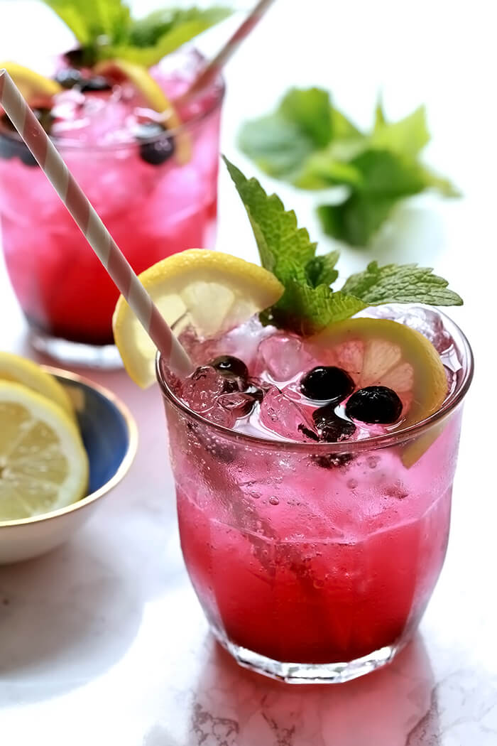 Two Sparkling Lemonade and Blueberry Cocktails with Lemon, Mint, and Blueberry Garnish