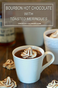 Bourbon Hot Chocolate with Toasted Meringue in a White Pottery Cup with Bourbon in Background