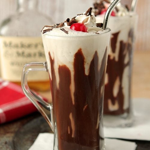 Hot Fudge and Bourbon Milkshake Served in a Ice Cream Soda Glass with a Stainless Steel Straw.