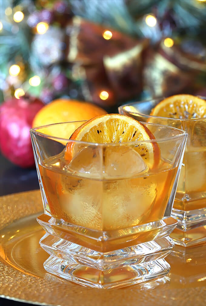 Bourbon and Orange Brulee Cocktail Closeup with a Round Ice Cube and a Bruleed Orange