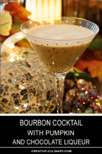 Bourbon Cocktail with Pumpkin and Chocolate Liqueur Served in a Gold Sparkle Martini Glass in Front of Sparkling Holiday Decor