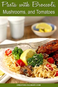 Pasta with Broccoli, Tomato, Mushrooms, and Parmesan Cheese Served with Chicken on a White Plate with Lemon Garnish