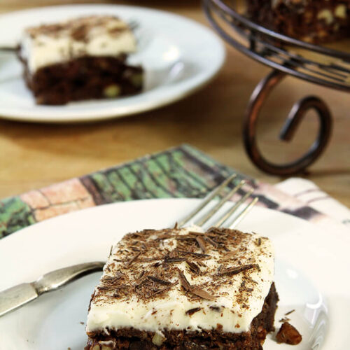 Slice of Chocolate Chip Brownies with Cream Cheese Frosting on a Round Plate