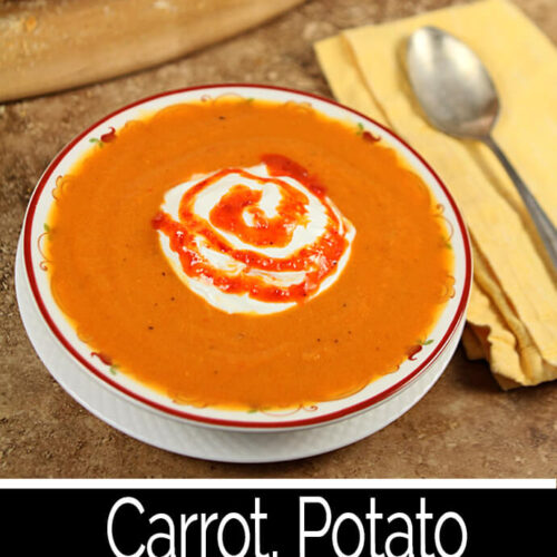 Carrot, Potato and Red Pepper Soup in a White Bowl Garnished with Sour Cream and Red Pepper Coulis