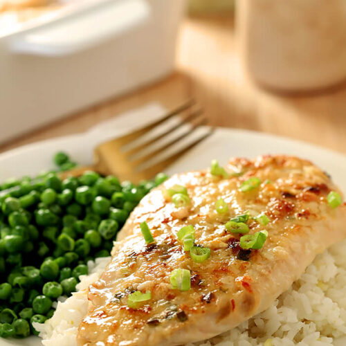 Serving of Broiled Chicken Parmesan on Rice with Green Peas