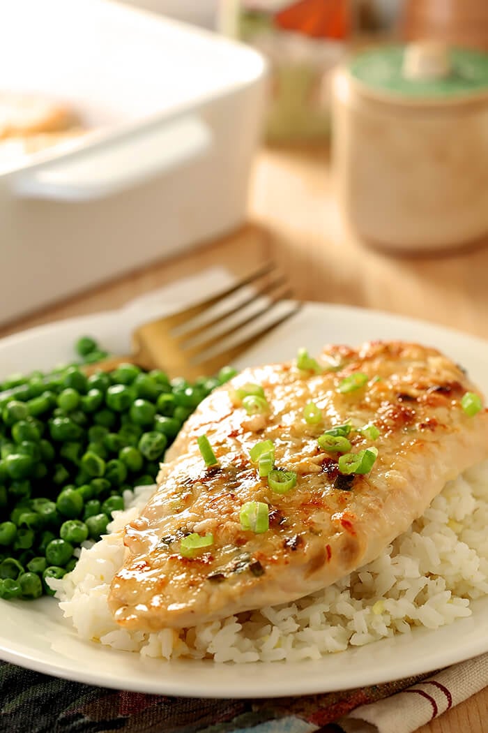 Serving of Broiled Chicken Parmesan on Rice with Green Peas