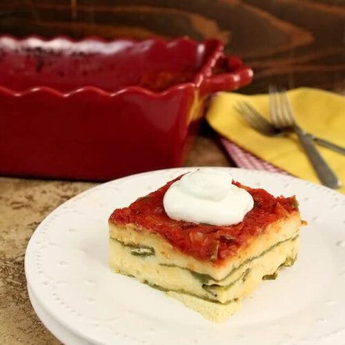 Chile Relleno Casserole served on a white plate with a dollop of sour cream on top.