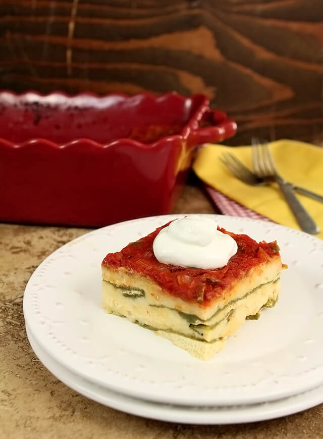 Chile Relleno Casserole served on a white plate with a dollop of sour cream on top.