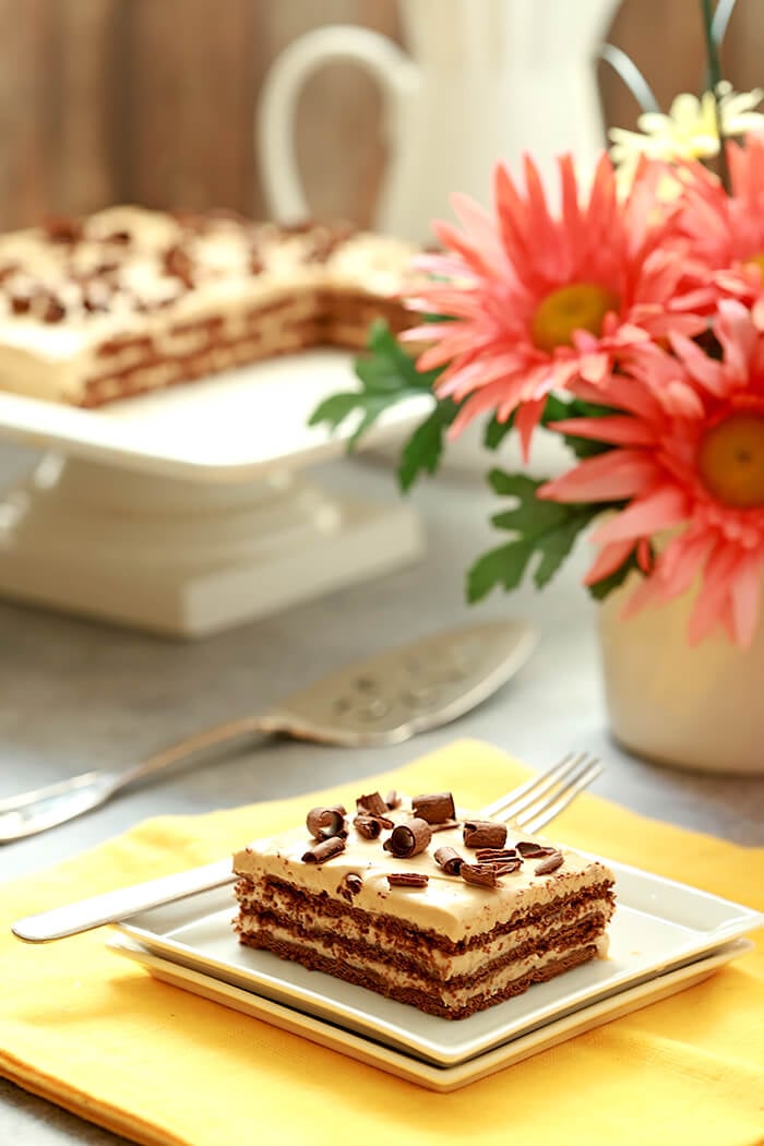 Chocotorta - An Argentinian Chocolate Cake Served with Chocolate Cake and Cake Plate in Background.