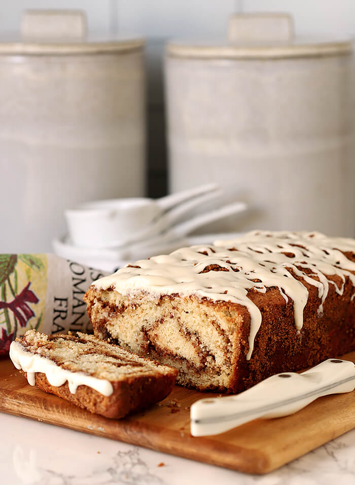 Cinnamon Roll Quick Bread with Cream Cheese Glaze Served on a Bread Board with Slices