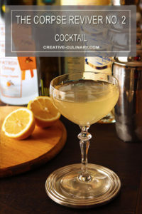 Corpse Reviver No 2 Cocktail in a Coupe Glass with Orange Halves in Background