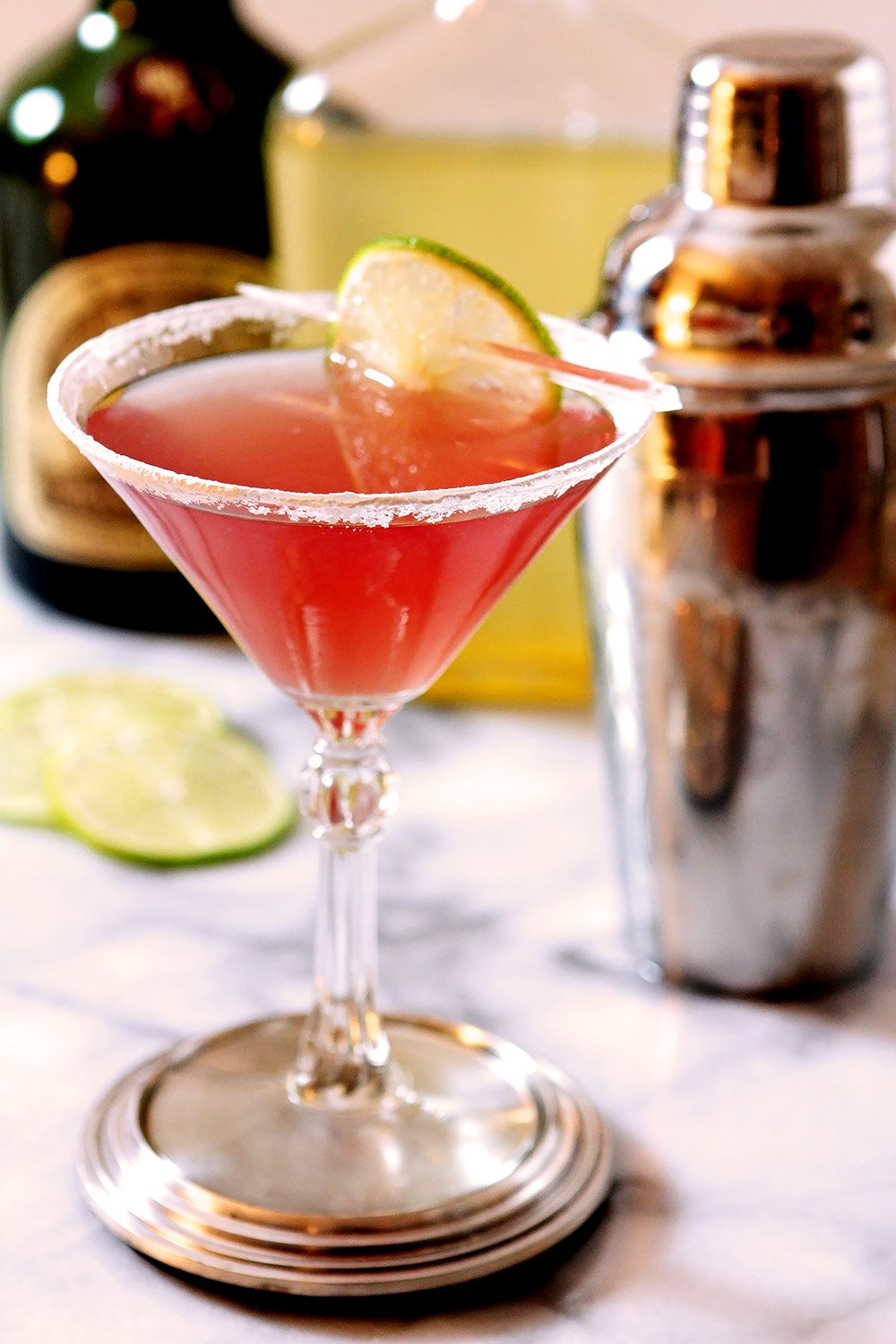 Cosmopolitan Cocktail on Marble Surface with Cocktail Shaker in Background.