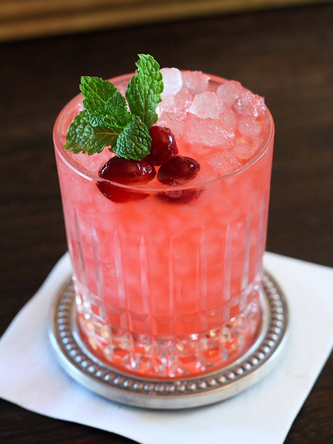 Cranberry Gin Fizz Cocktail in a cut crystal glass garnished with Cranberries and Mint.