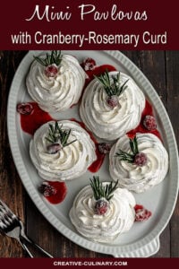 Mini Pavlovas with Cranberry Curd and Whipped Cream, garnished with Sugared Cranberries and a Sprig of Rosemary