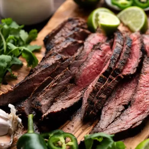 Sliced pieces of Carne Asada Mexican Flank Steak on a cutting board.