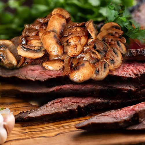 Flank Steak is Marinated and Grilled, then Sliced and Served with Sauteed Mushrooms and Onios