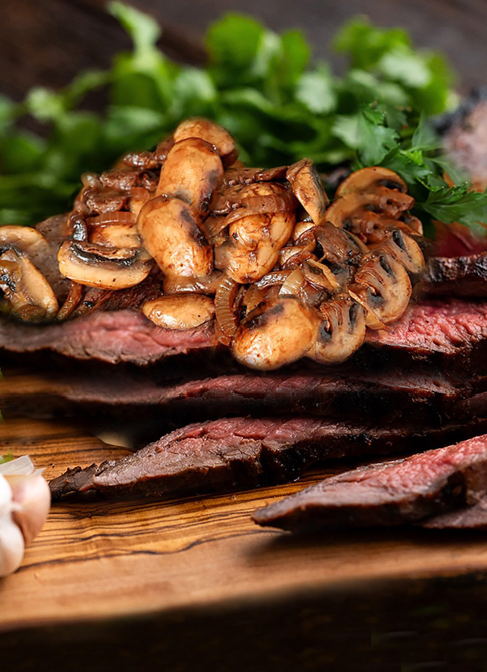 Flank Steak is Marinated and Grilled, then Sliced and Served with Sauteed Mushrooms and Onios