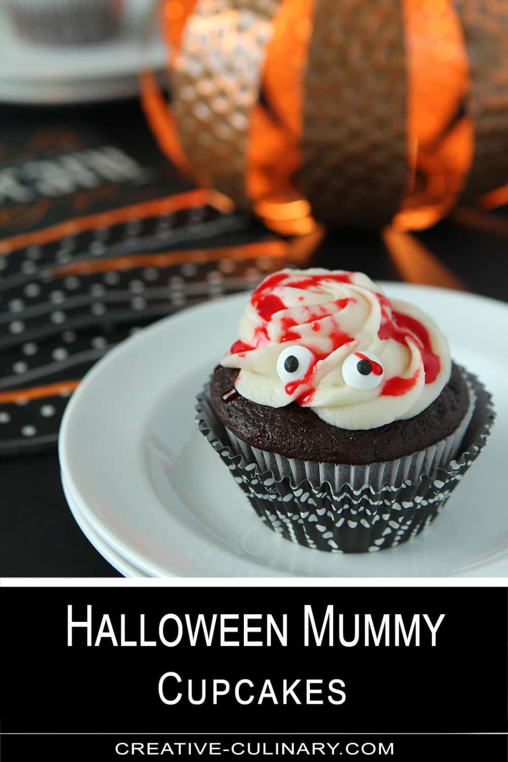 Chocolate Cupcakes with Buttercream Frosting and Red Simple Syrup made to look like a Halloween Mummy Cake on a white plate.