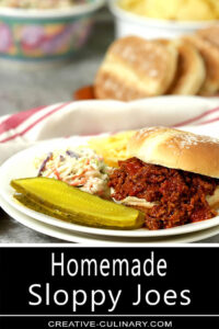 Homemade Sloppy Joes on White Plate with Chips, Slaw, and Pickles