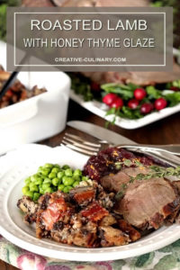 Roasted Lamb with Honey Thyme Glaze Served on a White Plate with Peas, Dressing, and Cranberry Sauce