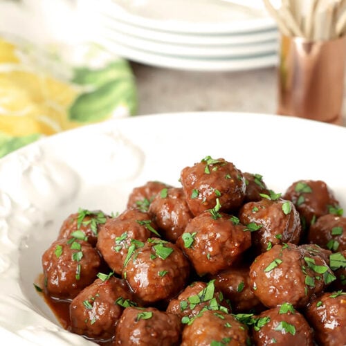 Grape Jelly and Chili Sauce Meatballs Served in a White Bowl with Parsley Garnish