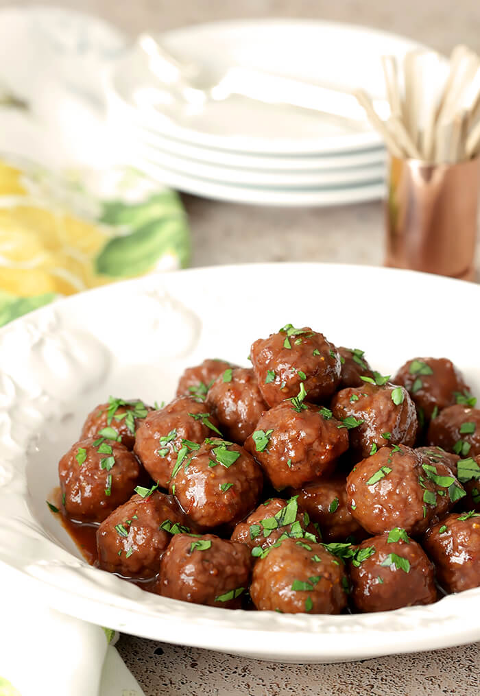 Grape Jelly and Chili Sauce Meatballs Served in a White Bowl with Parsley Garnish