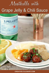 Serving of Meatballs with a Grape Jelly and Chili Sauce on a White Plate with Oranges, Cheese, and Crackers