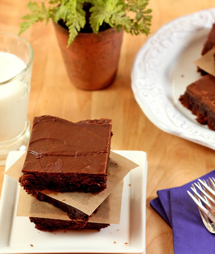 Mexican Brownies with Cinnamon and Cayenne Pepper Stacked Three High on a Plate with Milk and Purple Napkins