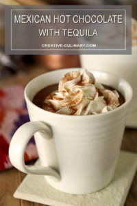 Mexican Hot Chocolate with Tequila Served in a White Mug with Whipped Cream on Top and Dusted with Cinnamon