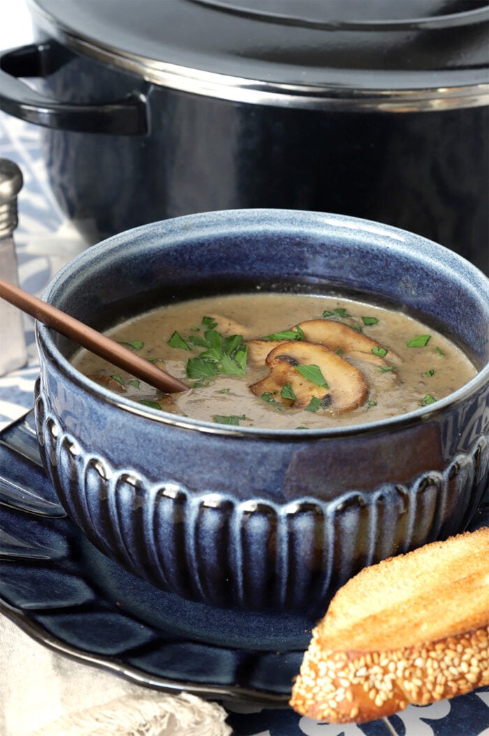 Homemade Cream of Mushroom Soup in a blue bowl with mushroom and parsley garnish.