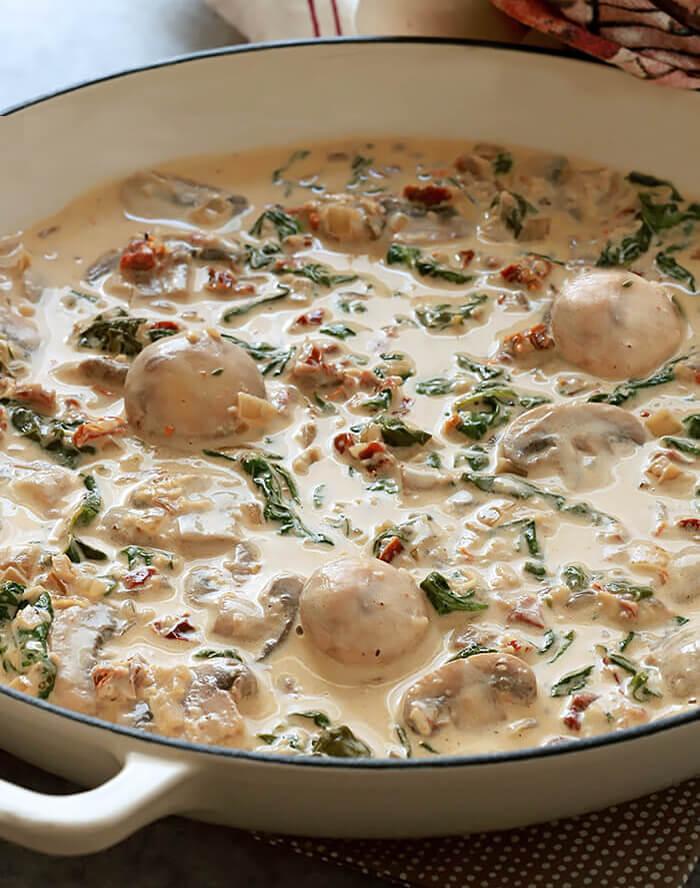 Creamy Mushroom Sauce with Sun-Dried Tomatoes and Spinach in Offwhite Skillet