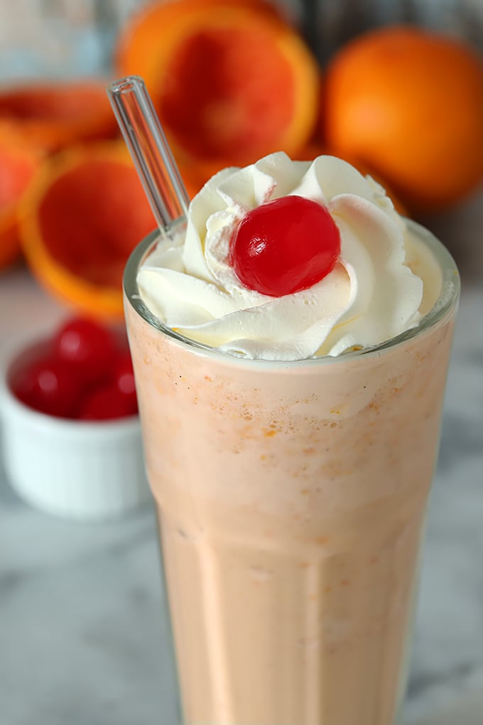 Fresh Orange Frosty Cocktail Closeup with Whipped Cream and Maraschino Cherry