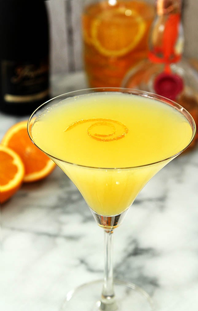 Orange Sunshine Martini on a Marble tabletop and garnished with an orange twist.