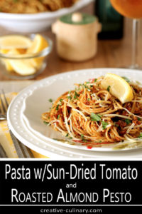 Serving of Pasta with Sun-Dried Tomato and Roasted Almond Pesto Served on Round White Decorative Plate